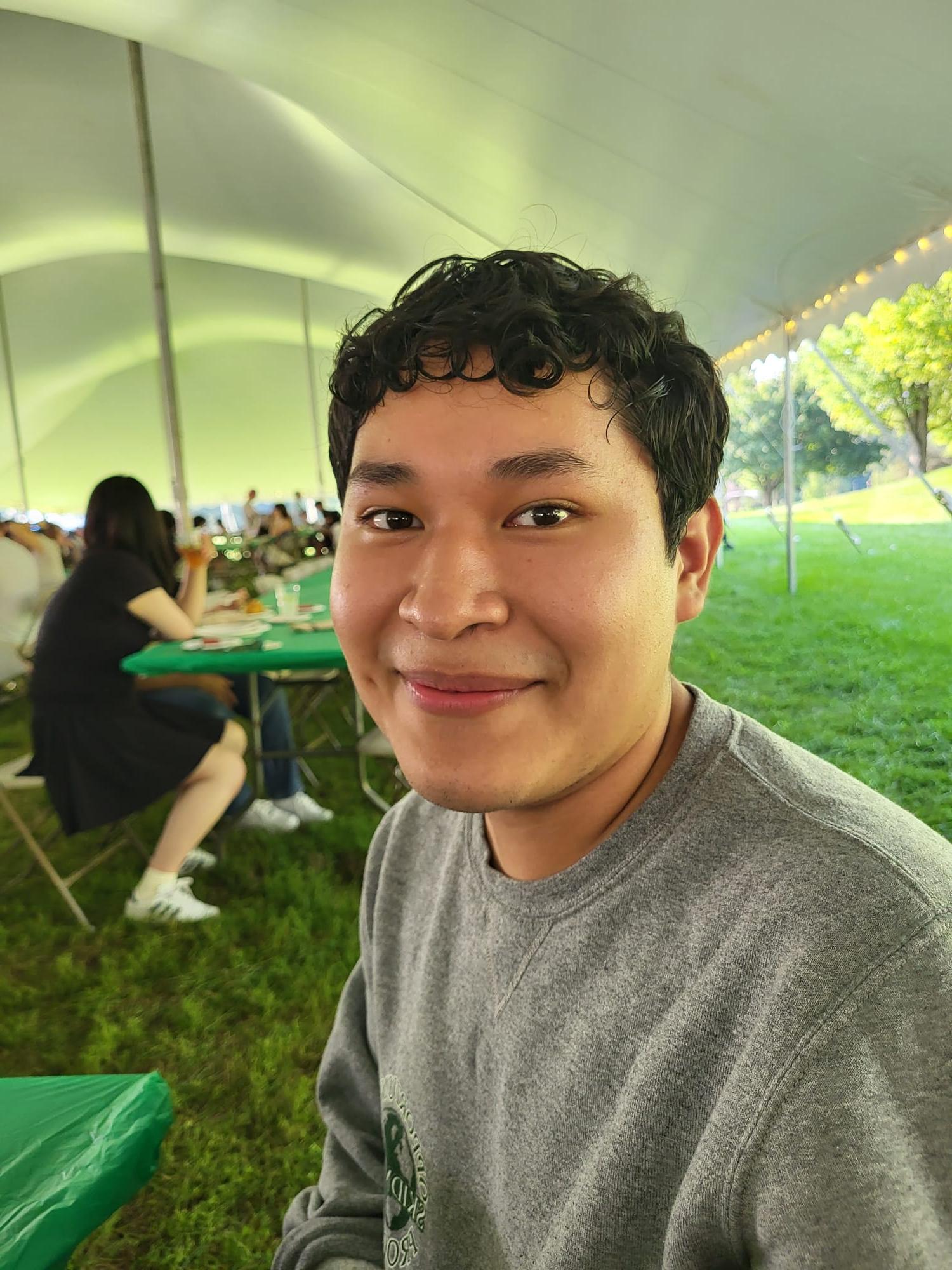 Matthew Olivos smiles at the camera. It's clear that the photo is taken from the inside of a tent during an event on South Lawn.