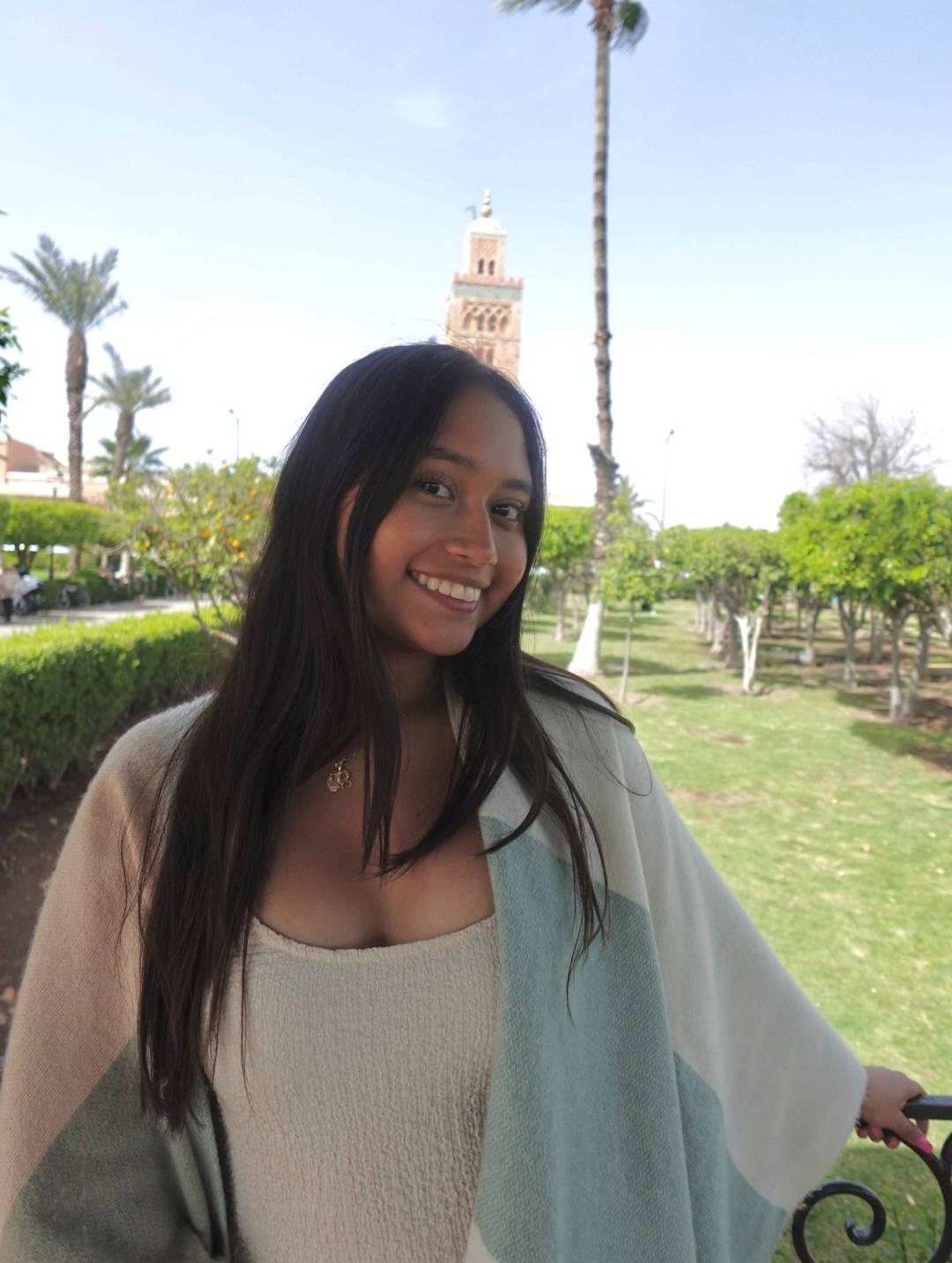 Cynthia Salas ’25 smiles at the camera; there are palm trees in the background.