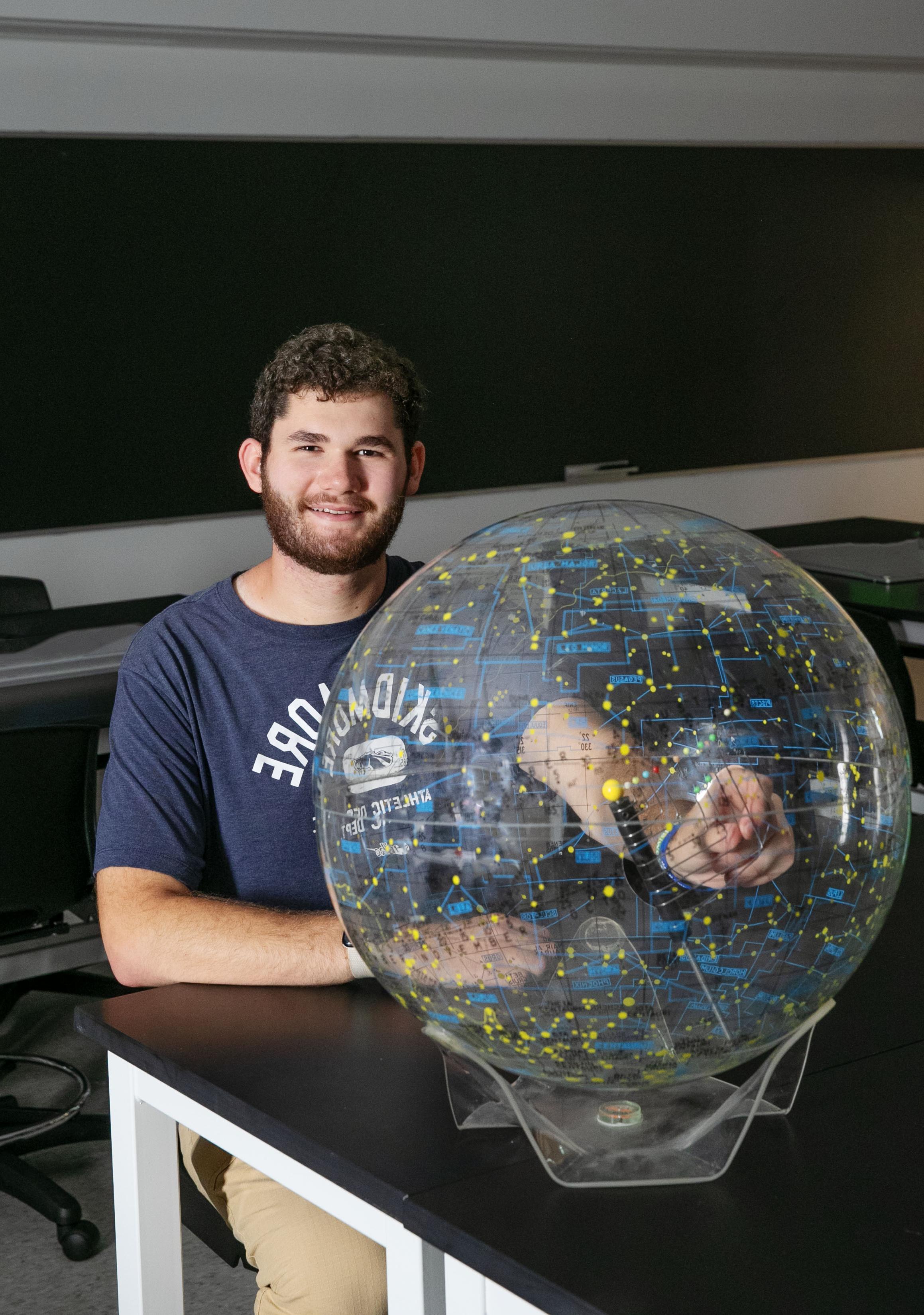 Milo Flamenbaum ’26 sits beside a plastic globe.